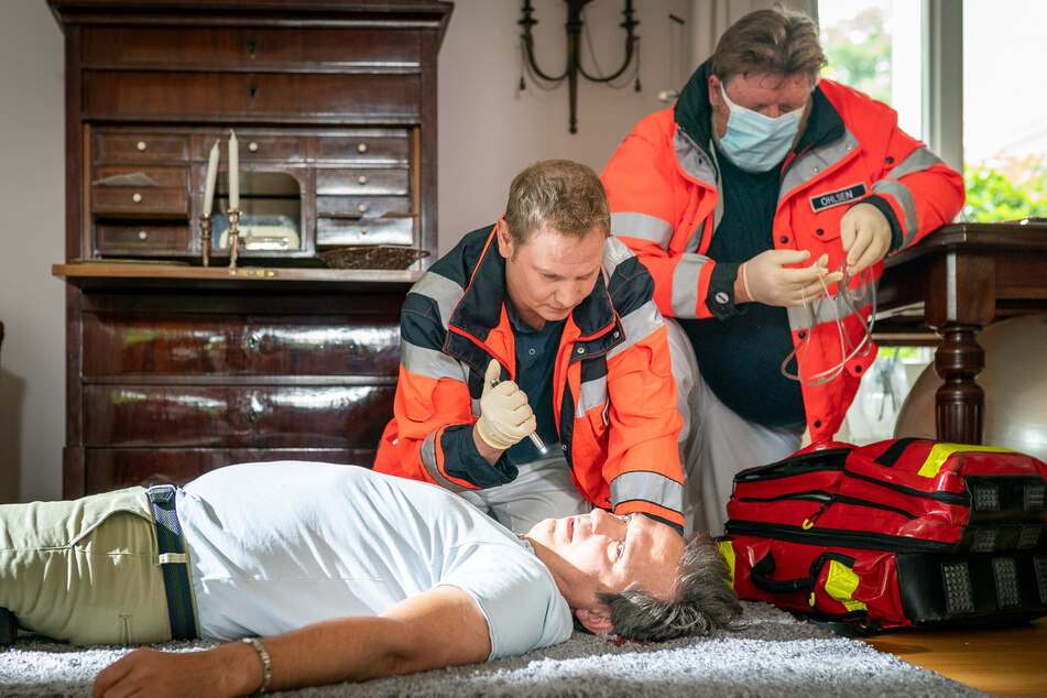 Dr. Haase (Fabian Harloff, M.) kümmert sich um den schwer verletzten Martin Preskow (Alexander Weise, l.), in dessen Villa mutmaßlich eingebrochen wurde.