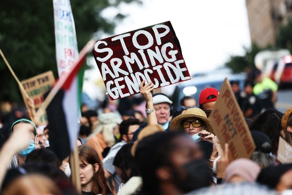 A demonstrator raises a sign reading "Stop Arming Genocide" during a protest outside a campaign event for Democratic presidential candidate Kamala Harris in New York City on August 14, 2024.