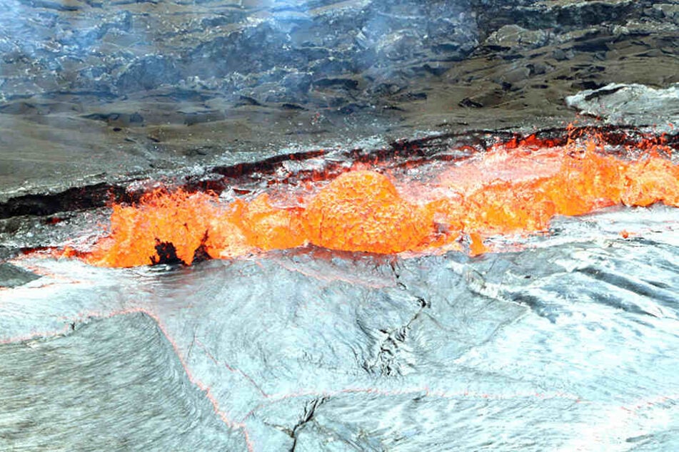 Lava spritzt am Rande eines Kraters nach oben.