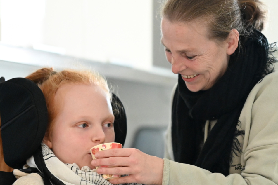 Martina Seibert reicht ihrer Tochter Ella einen Becher mit Wasser.