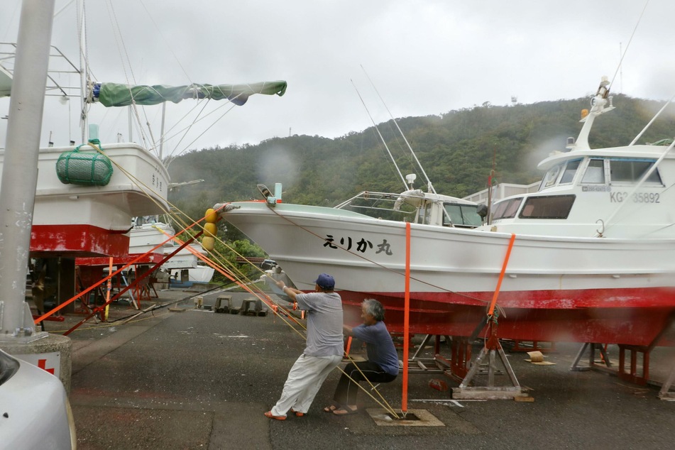 Zwei Männer holen an einem Hafen in der Südwestlichen Präfektur Kagoshima Schiffe aus dem Wasser.