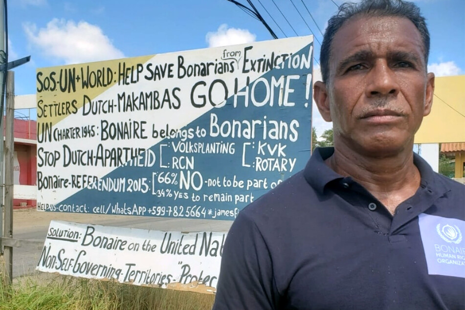 James Finies stands next to a protest sign for the independence of Bonaire stands along a road in the capital city of Kralendijk.