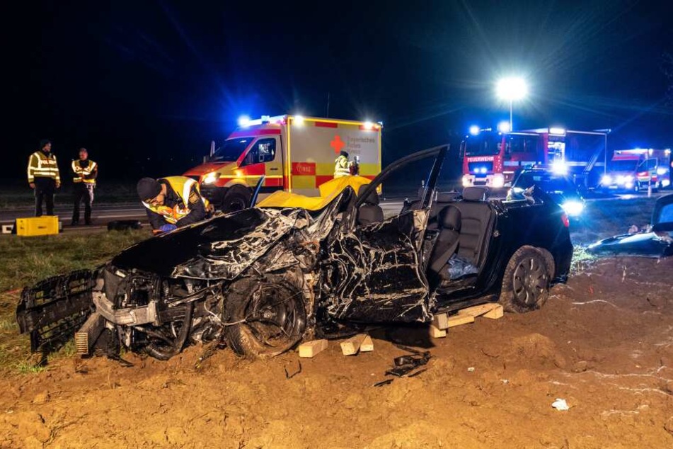 Ein Polizist steht neben der Bundesstrasse 12 an einem bei einem Unfall zerstörten Auto.