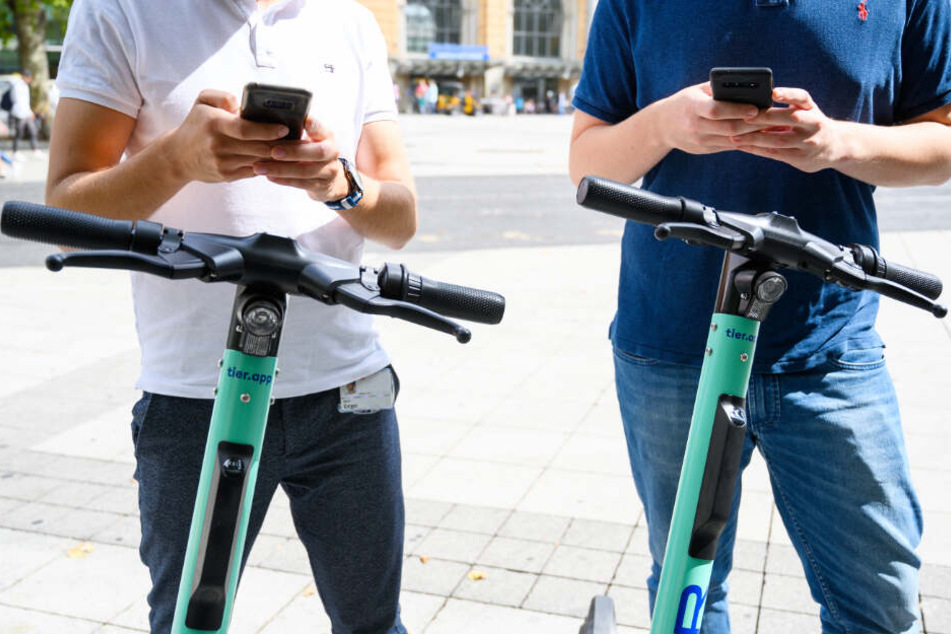 Zwei Männer leihen sich per Handy-App E-Scooter aus. (Symbolbild)