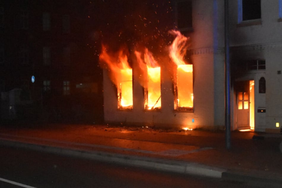 Flammen schlagen aus den Fenstern des Mehrfamilienhauses.