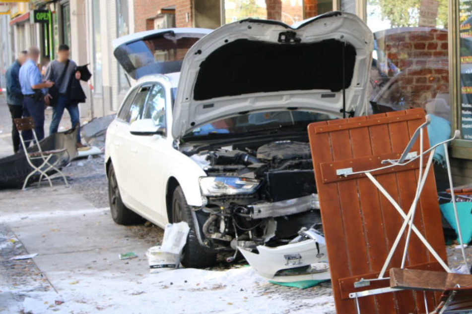 Der stark beschädigte weiße Audi vor dem Café.