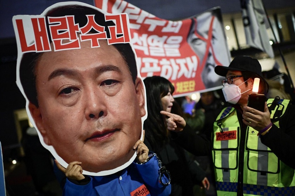 A protester holding a cardboard reading "Leader of insurgents" on an image depicting the face of South Korea's President Yoon Suk Yeol takes part in a protest calling for his ouster outside the National Assembly in Seoul on December 8, 2024.