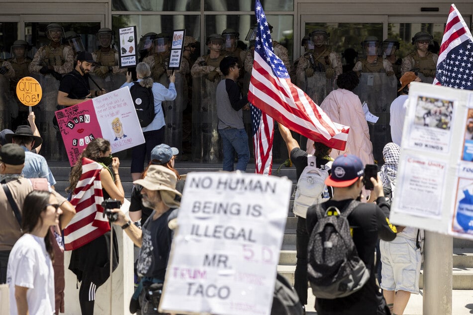 Demonstrators gather in front of the Federal Building guarded by US Marines and National Guard troops during the "No Kings" protest following federal immigration raids, in Los Angeles, California, on July 4, 2025.