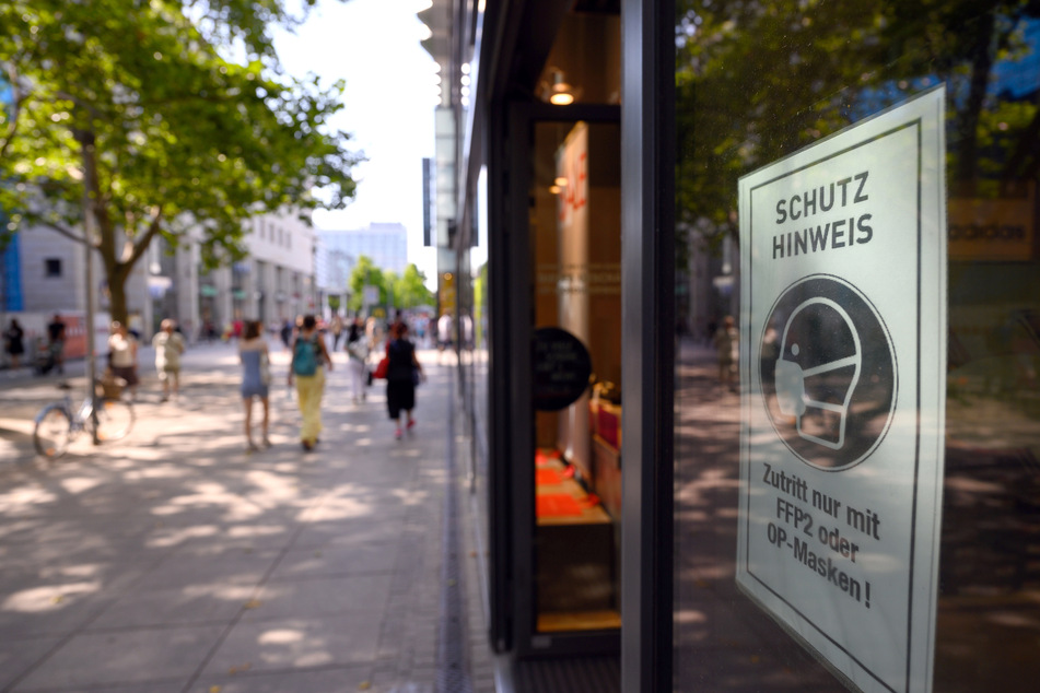 Ein Schild mit dem Hinweis auf die Maskenpflicht klebt am Schaufenster eines Modegeschäfts auf der Einkaufsmeile Prager Straße. Bleibt die Inzidenz weiter über 10, könnten bisherige Lockerungen zurückgenommen werden.