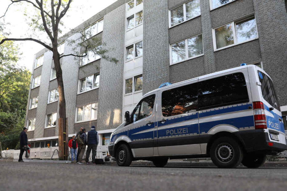 Ein Polizeiauto steht vor einem Haus in Hamburg, in dem eine Wohnung durchsucht wird.