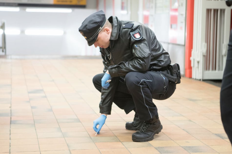 Ein Polizist sichert mit einem Wattestäbchen Spuren am Tatort.