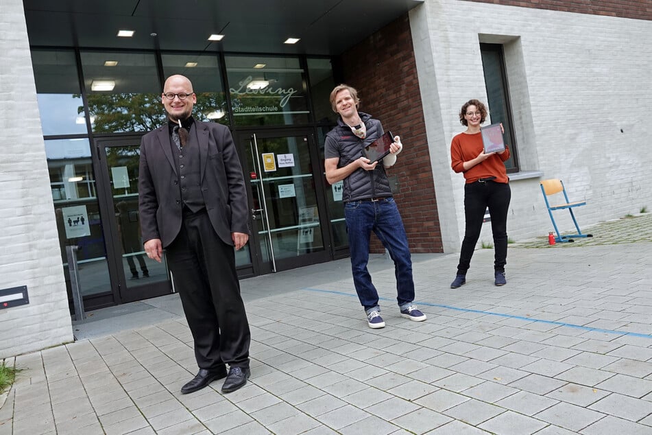Schulleiter Tobias Stapelfeld (l.) sowie das Lehrerteam Hinrich Bühlker und Merle Heintz stehen vor dem Schuleingang der Lessing-Stadtteilschule in Hamburg-Harburg.