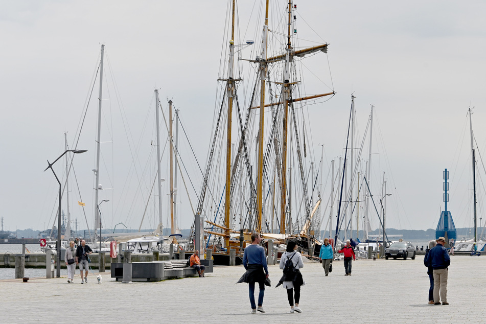 Besucher gehen am Hafen von Eckernförde entlang.
