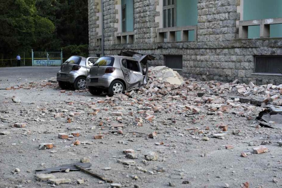 Zwei beschädigte Autos liegen nach einem Erdbeben unter den Trümmern vor dem Gebäude der Geologie-Fakultät.