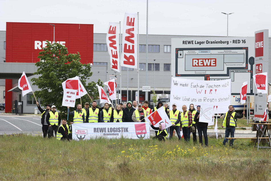 Vor einem Rewe-Lager protestieren Beschäftigte für bessere Arbeitsbedingungen. (Archivbild)