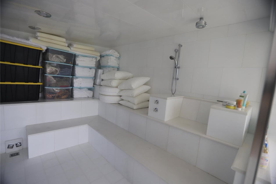 Eine riesige Dusche mit Sitzmöglichkeiten und Kissen.