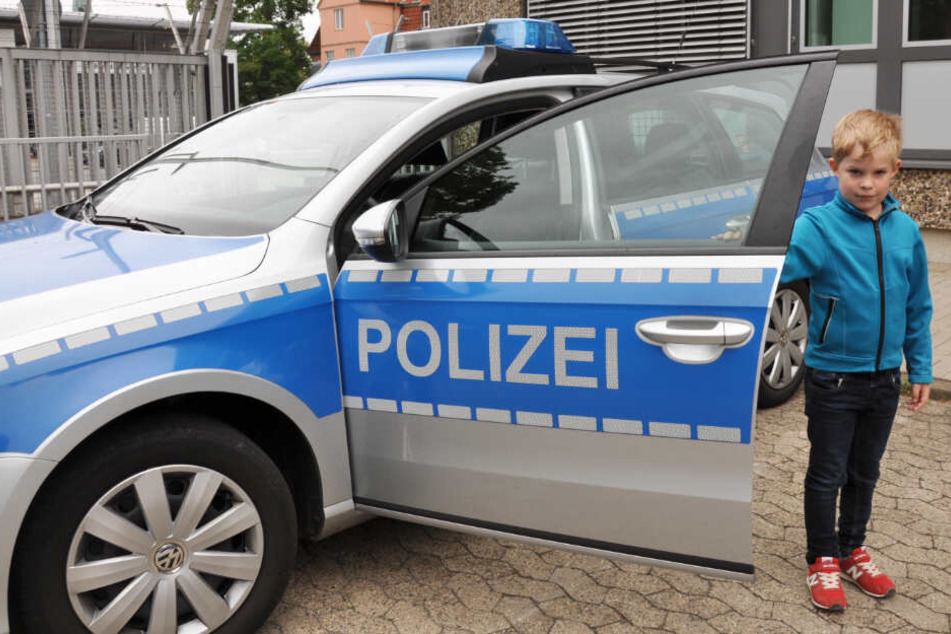 Paul posiert schon mal neben einem Polizeifahrzeug.