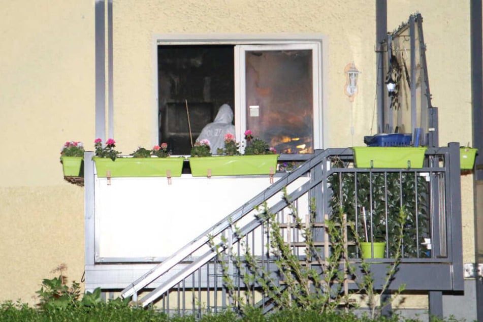 Ein Polizist steht im weißen Overall in der ausgebrannten Wohnung.