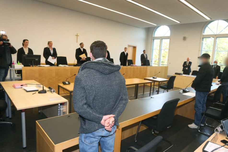 Der Hauptangeklagte (l) steht im Gerichtssaal des Landgerichtes neben den zwei Mitangeklagten. Drei junge Männer müssen sich vor Gericht verantworten weil sie an einer Auseinandersetzung mit tödlichem Ausgang in der Augsburger Innenstadt beteiligt waren.