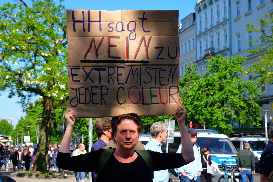 Mehrere Menschen gehen bei der Gegendemo gegen Islamismus auf die Straße und halten Forderungen auf Schildern hoch.