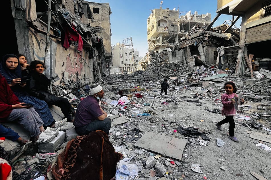 Palestinians sit next to the body of a relative as they look at the rubble of their building after an Israeli strike in Beit Lahia, in the northern Gaza Strip on Tuesday.