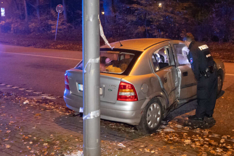 Ein Polizist untersucht das beschädigte Auto, dessen Fahrt am Laternenmast endete.