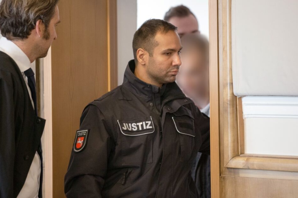 Verteidiger Frank Otten (l.) wartet auf seinen Mandanten (r., verdeckt), der gerade von Justizbeamten in den Gerichtssaal geführt wird.