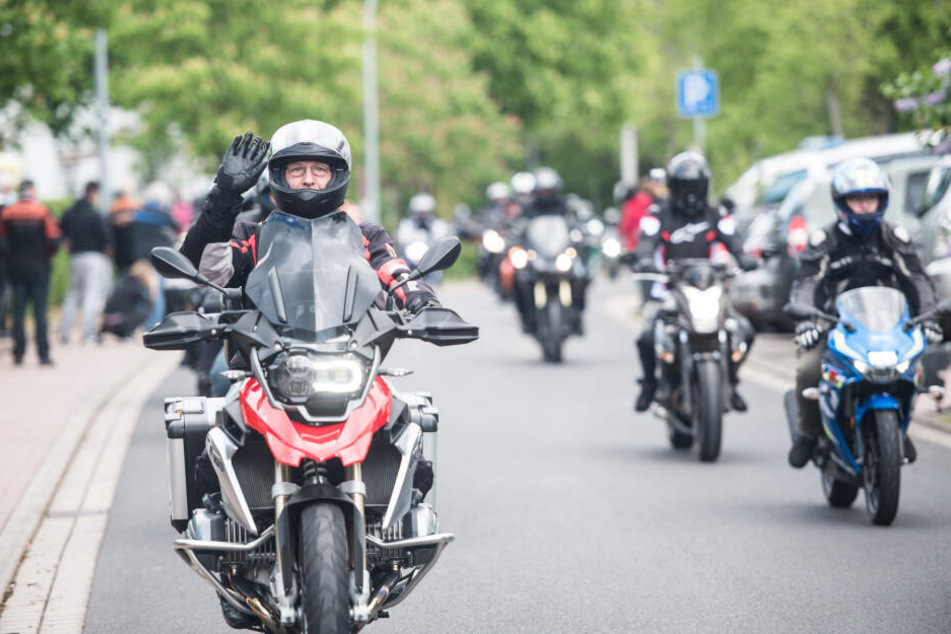 Ein Biker grüßt gut gelaunt einen Fotografen.