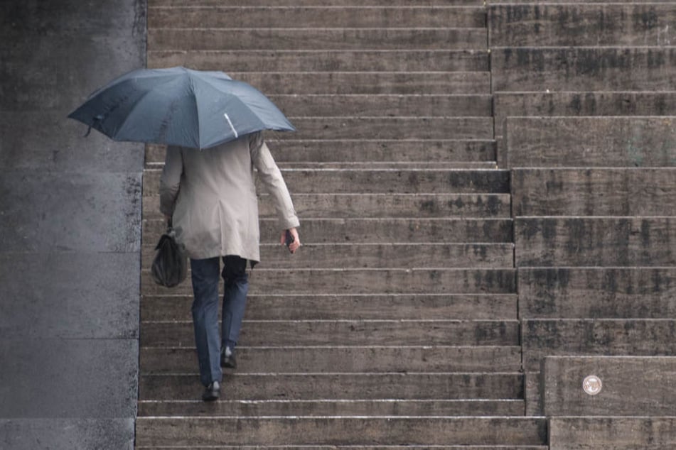 Ein Mann geht die Treppen auf dem Schlossplatz in Stuttgart bei Regen hoch. Regen sorgt für den Anstieg des Wasserstands im Rhein.