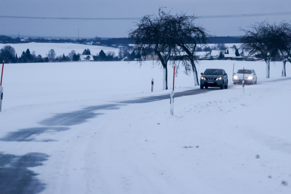 Stollberg: Autos fahren über eine verschneite Straße im Erzgebirge. Eine in der Nacht durchziehende Schneefront hat für reichlich neuen Schnee gesorgt.