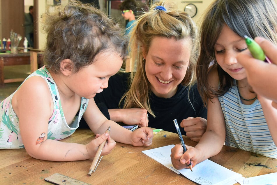 In der Schreib- und Druckwerkstatt im Buchkindergarten vom Verein Buchkinder e.V. malen und schreiben die Kinder Laszlo (l) und Rala (r) mit Werkpädagogin Janina Werner auf verschiedene Blätter, die anschließend zu einem kleinen Buch gebunden werden sollen.