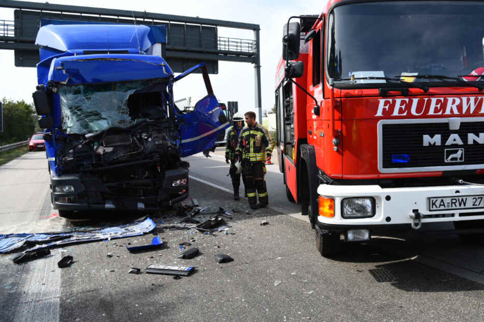 Einer der beiden Lkw, die am Unfall beteiligt waren. Außerdem geht die Feuerwehr an der Unfallstelle ihrer Arbeit nach.