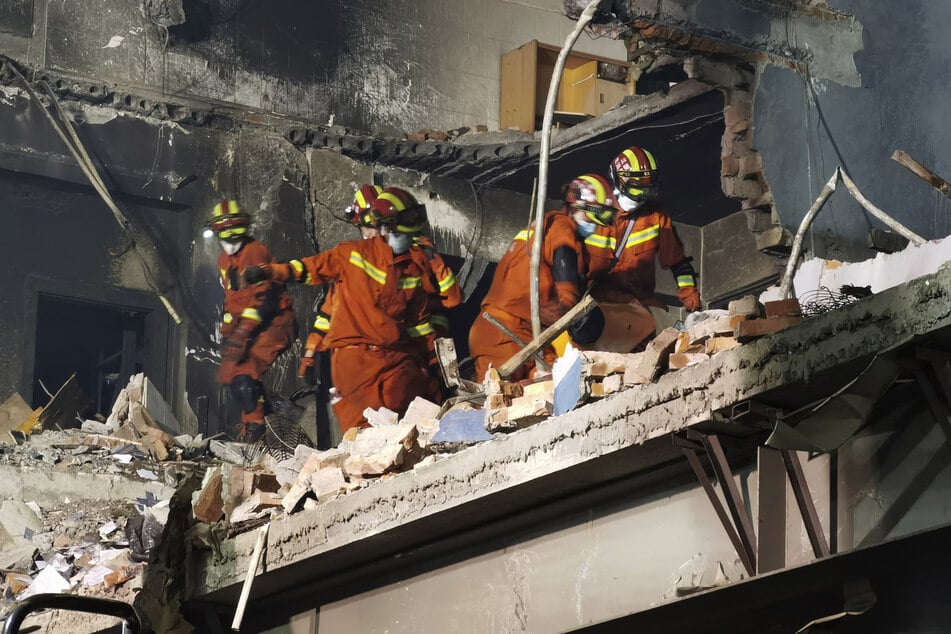 Feuerwehrleute suchen nach Opfern in einem beschädigten Gebäude nach der Explosion des Tanklastwagens.