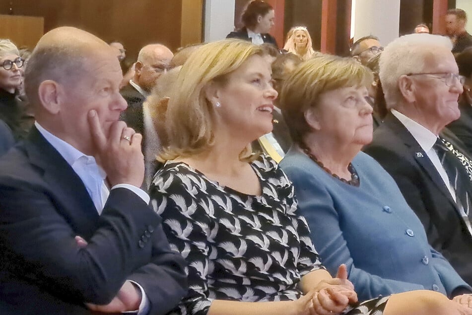 Ex-Kanzler Olaf Scholz (67, SPD, v.l.n.r.), Bundestagspräsidentin Julia Klöckner (53, CDU), Ex-Kanzlerin Angela Merkel (71, CDU) und Winfried Kretschmann (77, Bündnis 90/Die Grünen) sitzen bei der Abschiedsveranstaltung nebeneinander.