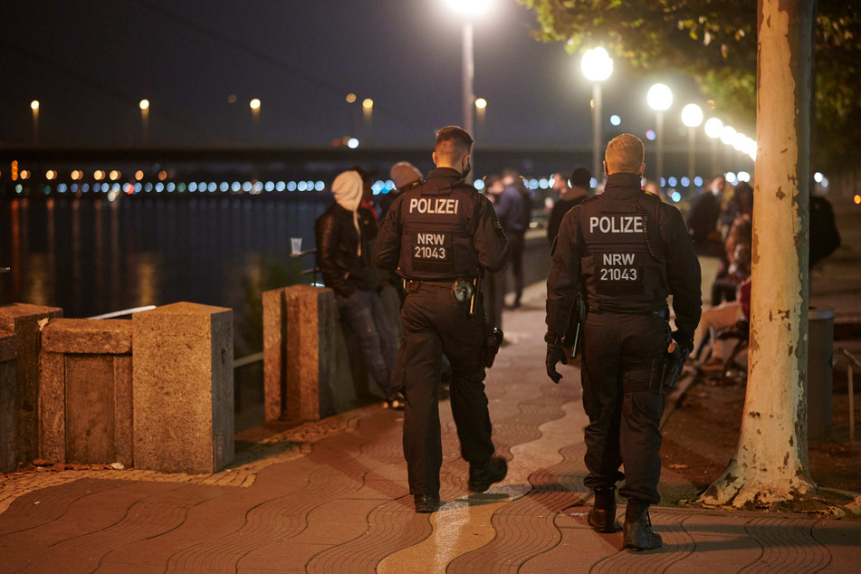 Polizisten patrouillieren an der Düsseldorfer Rheinpromenade, nachdem ab 23 Uhr zum ersten Mal die Sperrstunde als Maßnahme gegen die Verbreitung des Coronavirus gilt.