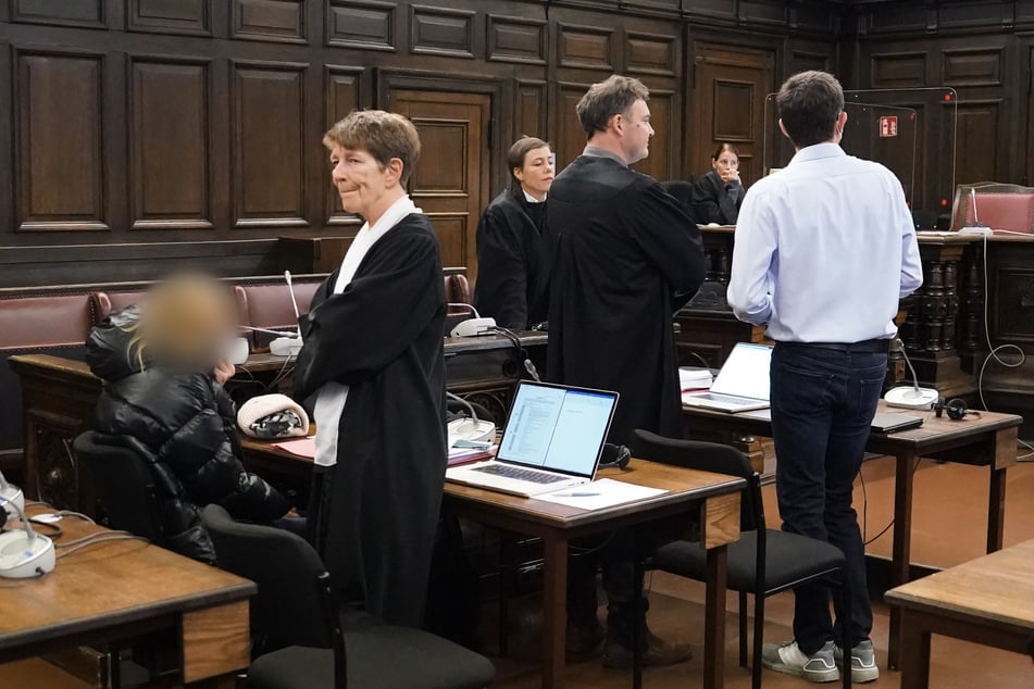 Das angeklagte Ehepaar (l und r) steht zu Beginn des Prozesses wegen versuchter Anstiftung zum Mord im Sitzungssaal im Strafjustizgebäude neben der Rechtsanwältin Gabriele Heinecke (2.v.l) und Rechtsanwalt Arne Timmermann (2.v.r).