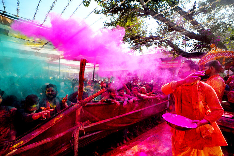 Hinduistische Anhänger zerstreuen während der Feierlichkeiten zum Holi-Fest farbiges Pulver und Wasser in Mathura, Indien.