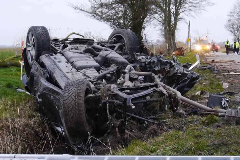 Das Wrack des Autos liegt auf dem Dach am Straßenrand.