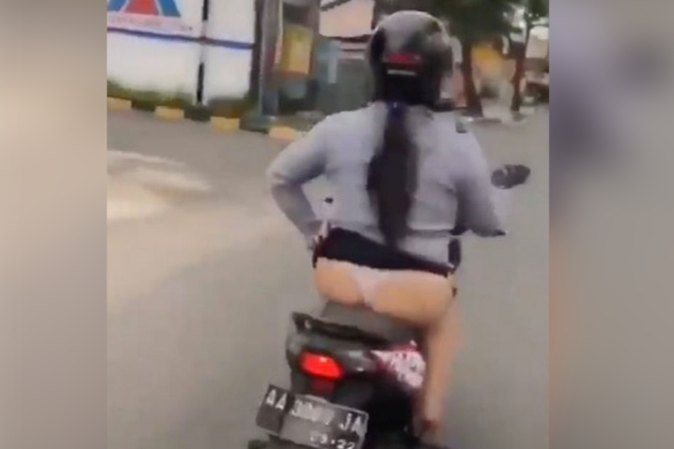 Die unbekannte Dame hebt den Rock während ihrer Roller-Fahrt nach oben.