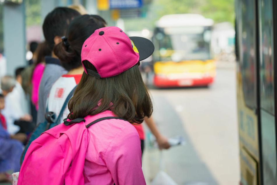 Kinder warten gemeinsam an einer Haltestelle auf den Schulbus.