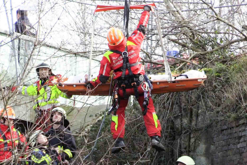 Höhenretter der Feuerwehr retten in einem Tragekorb eine Frau aus einem Schacht.