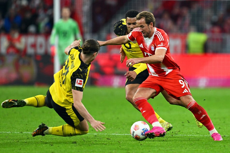 Harry Kane (r, Bayern München) in Aktion gegen Marcel Sabitzer (l, Borussia Dortmund) und Felix Nmecha (Borussia Dortmund).