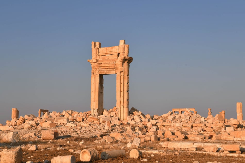 Ein Teil eines historischen Bauwerkes aus römischer Zeit steht in der antiken Oasenstadt Palmyra zwischen Trümmern.