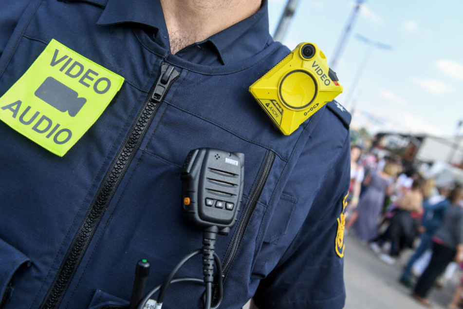 Ein Polizist mit Bodycam geht über das Oktoberfest auf der Theresienwiese.