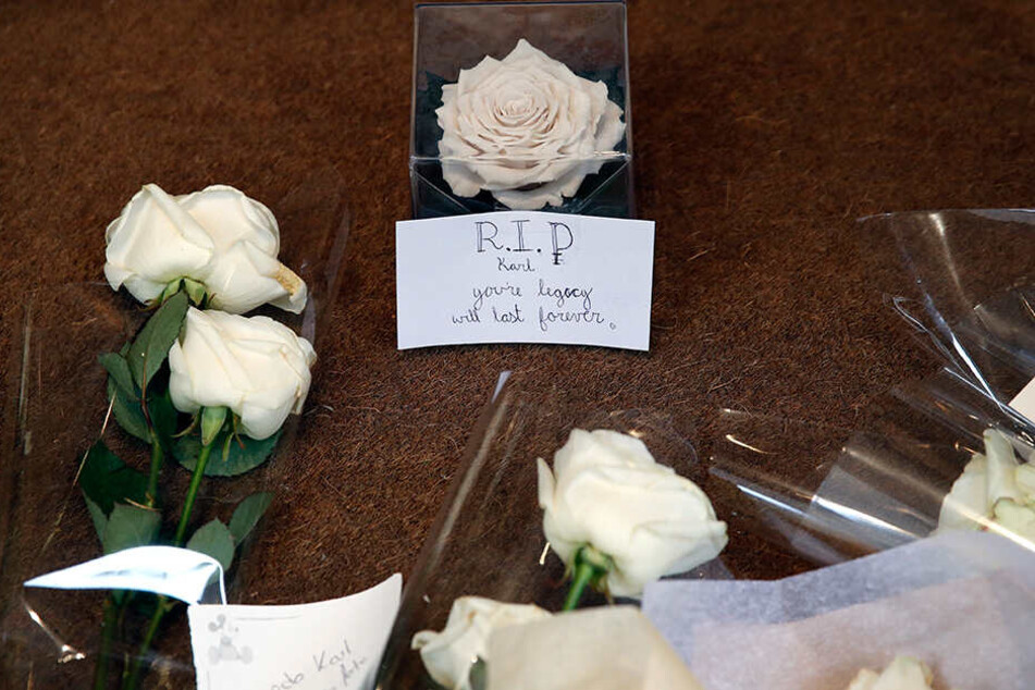 Blumen und ein Zettel liegen am Eingang der Chanel-Zentrale in Paris. Sie wurden von Passanten dort abgelegt, um dem verstorbenen Modeschöpfer Karl Lagerfeld zu gedenken.