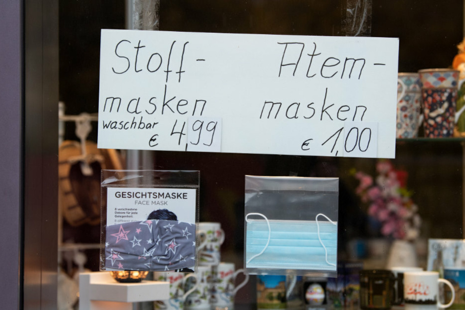 Ein Schild hängt an einer Glasscheibe eines Geschäfts unweit des Alexanderplatzes und wirbt für Masken gegen das neuartige Coronavirus.