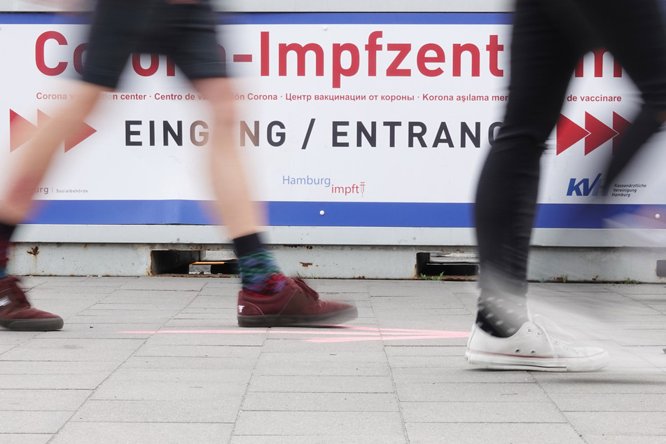 Passanten gehen zum Eingang des Impfzentrums.