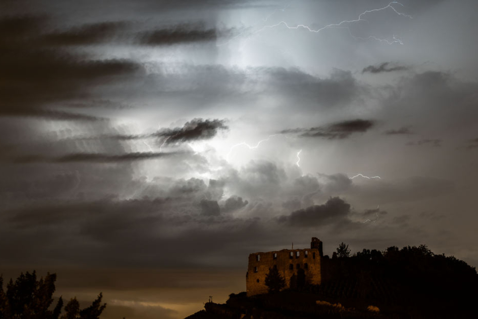 Blitze eines über das Elsass und Südbaden ziehenden Gewitters zeichnen sich hinter der Ruine der Burg von Staufen im Breisgau am Himmel ab.