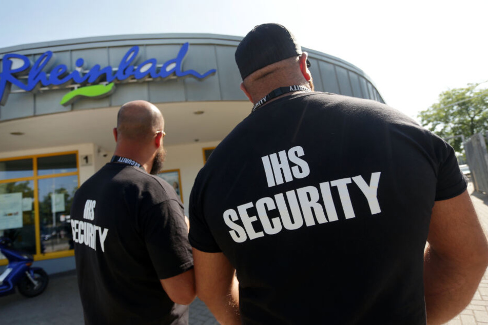 Zwei Männer des Sicherheitsdienstes IHS Security stehen vor dem Eingang des Rheinbades.