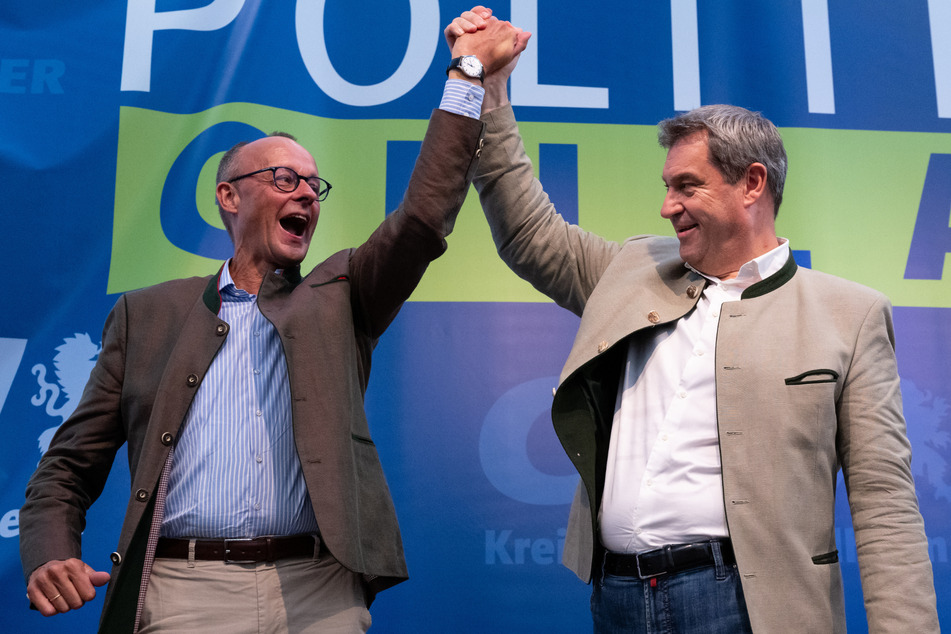 Markus Söder (56, CSU, r.), Ministerpräsident von Bayern, und Friedrich Merz (67), Bundesvorsitzender der CDU, jubeln beim Politischen Frühschoppen Gillamoos auf der Bühne.